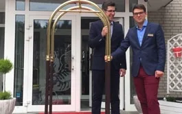 Representative hotel space: Hotel entrance with two staff members standing beside a brass luggage cart.