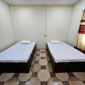 Espacio representativo del hotel: Un dormitorio con dos camas, suelo de baldosas y una cortina.