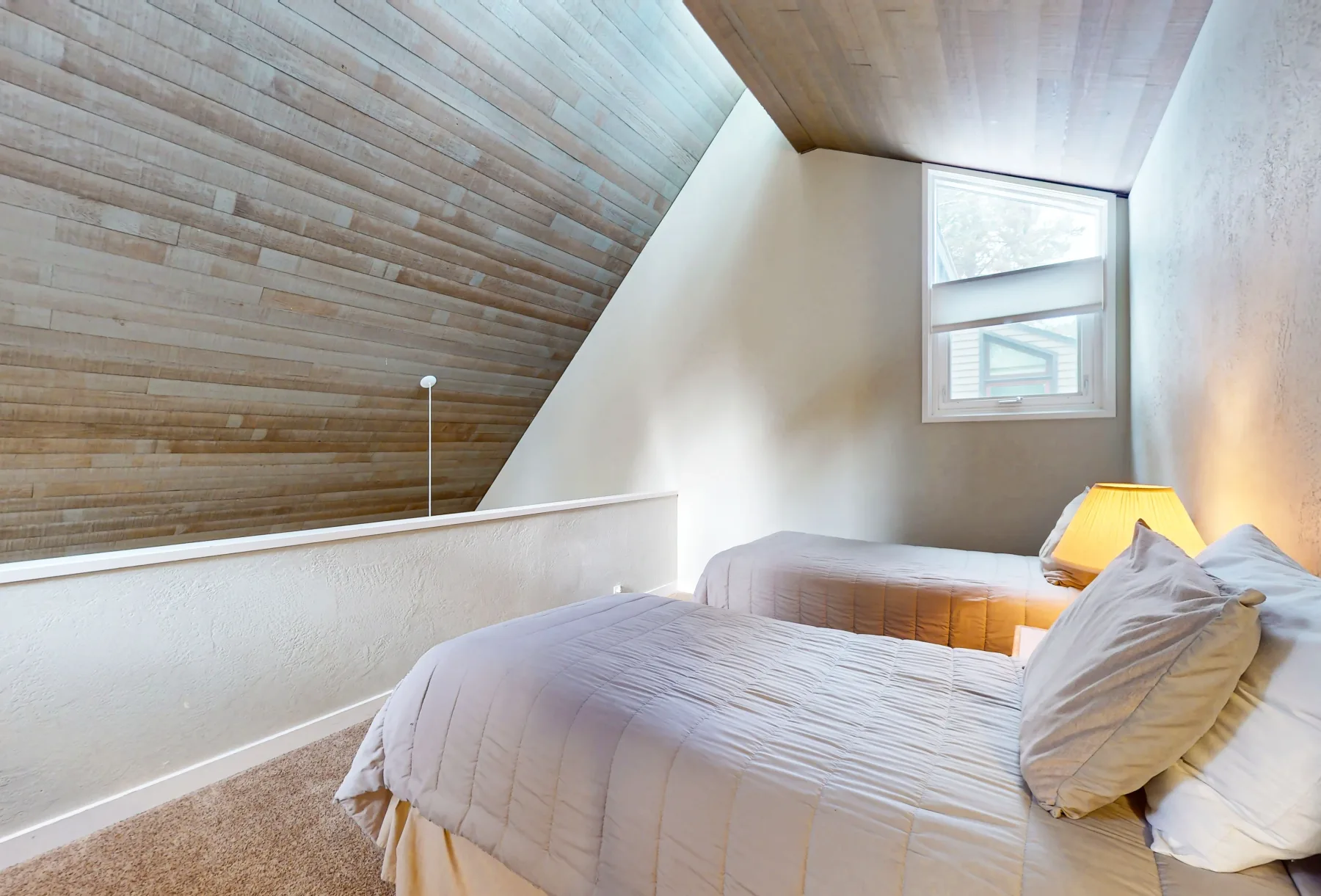 Un dormitorio con una cama bajo un techo inclinado revestido de madera.