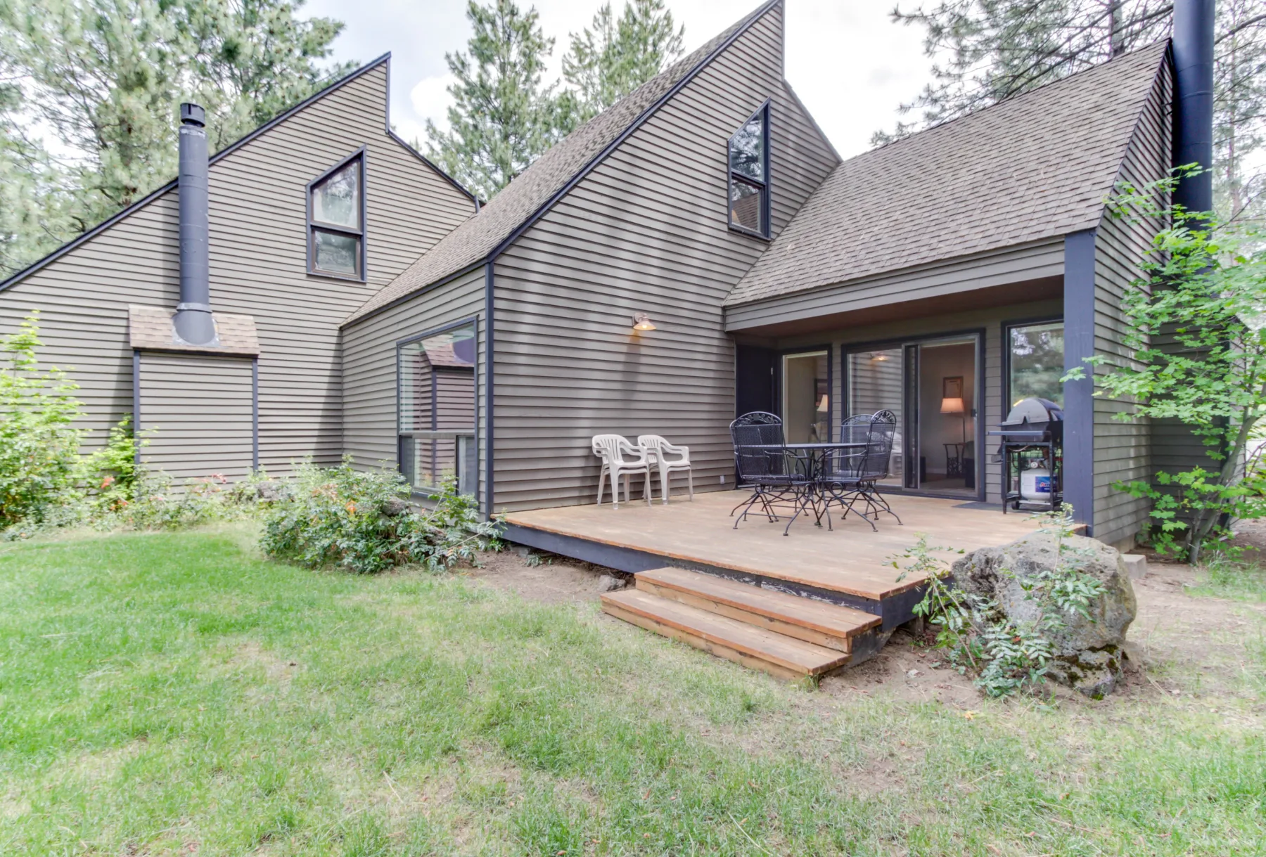 Exterior de una casa con una terraza elevada de madera y asientos al aire libre.