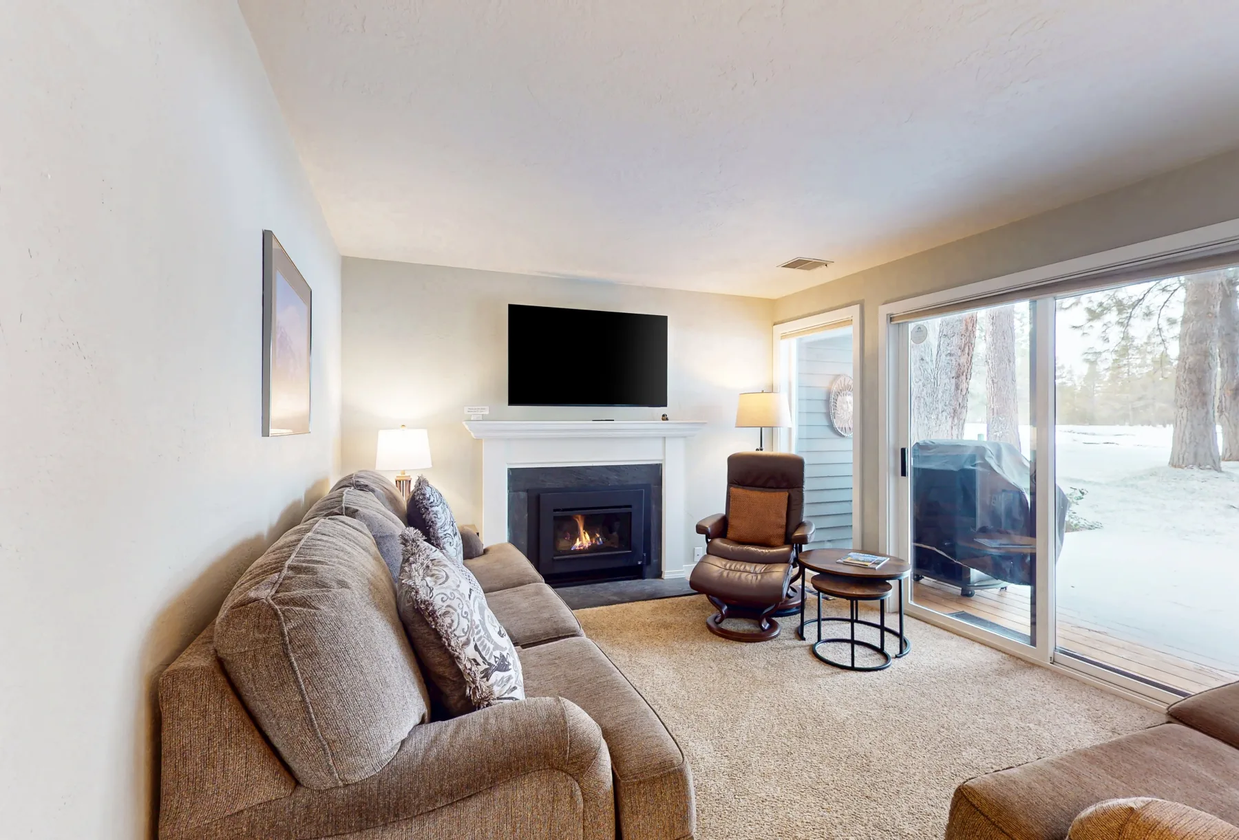 Sala de estar con chimenea, asientos y puertas corredizas de vidrio que dan a un patio.