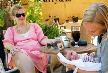 Representative hotel space: Outdoor café scene with two women seated beside a table and a baby.