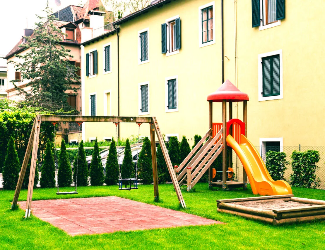 Representative hotel space: Outdoor playground with slides, swings, and a grassy play area.