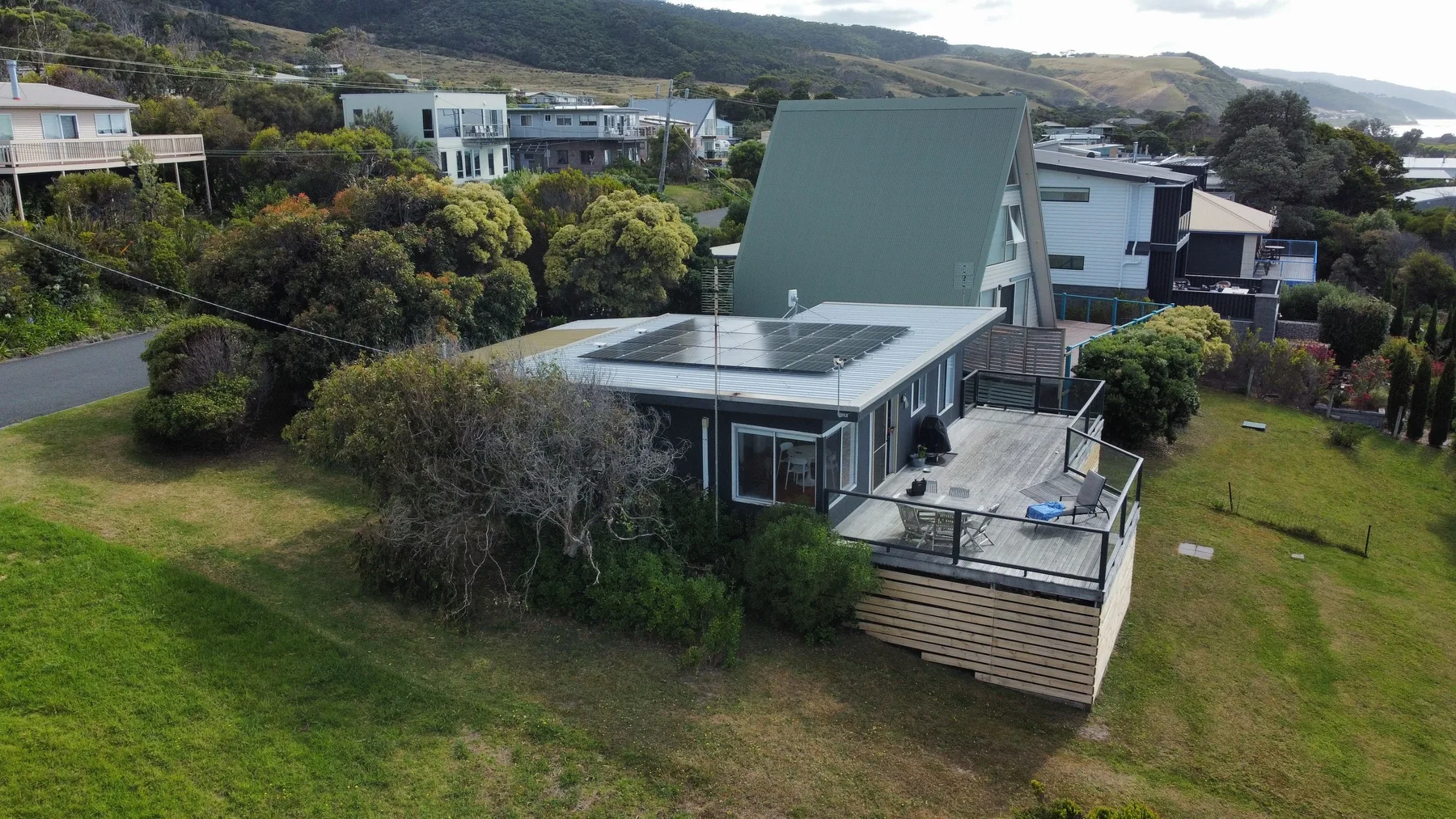 A modern house with a broad lawn and an outdoor deck.