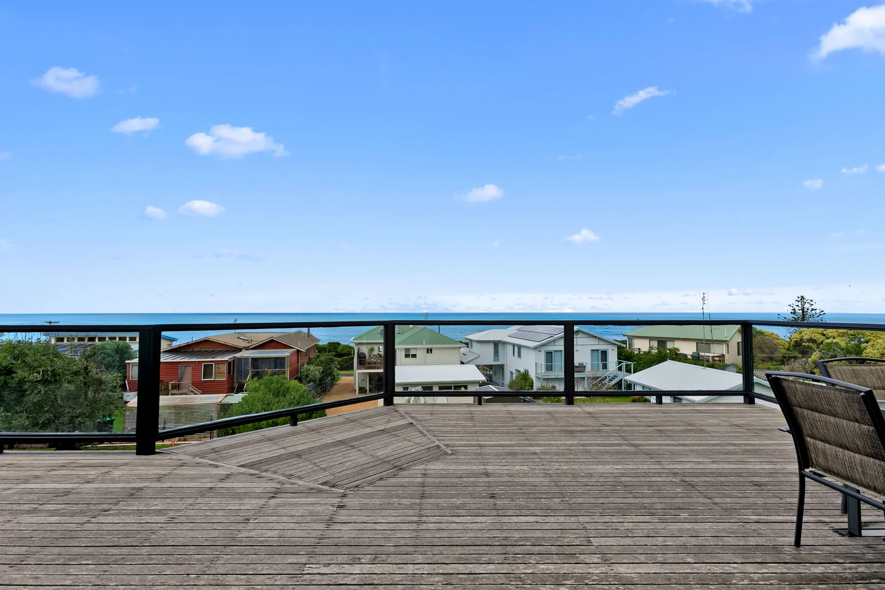 A wooden deck overlooks nearby houses beneath a clear blue sky.