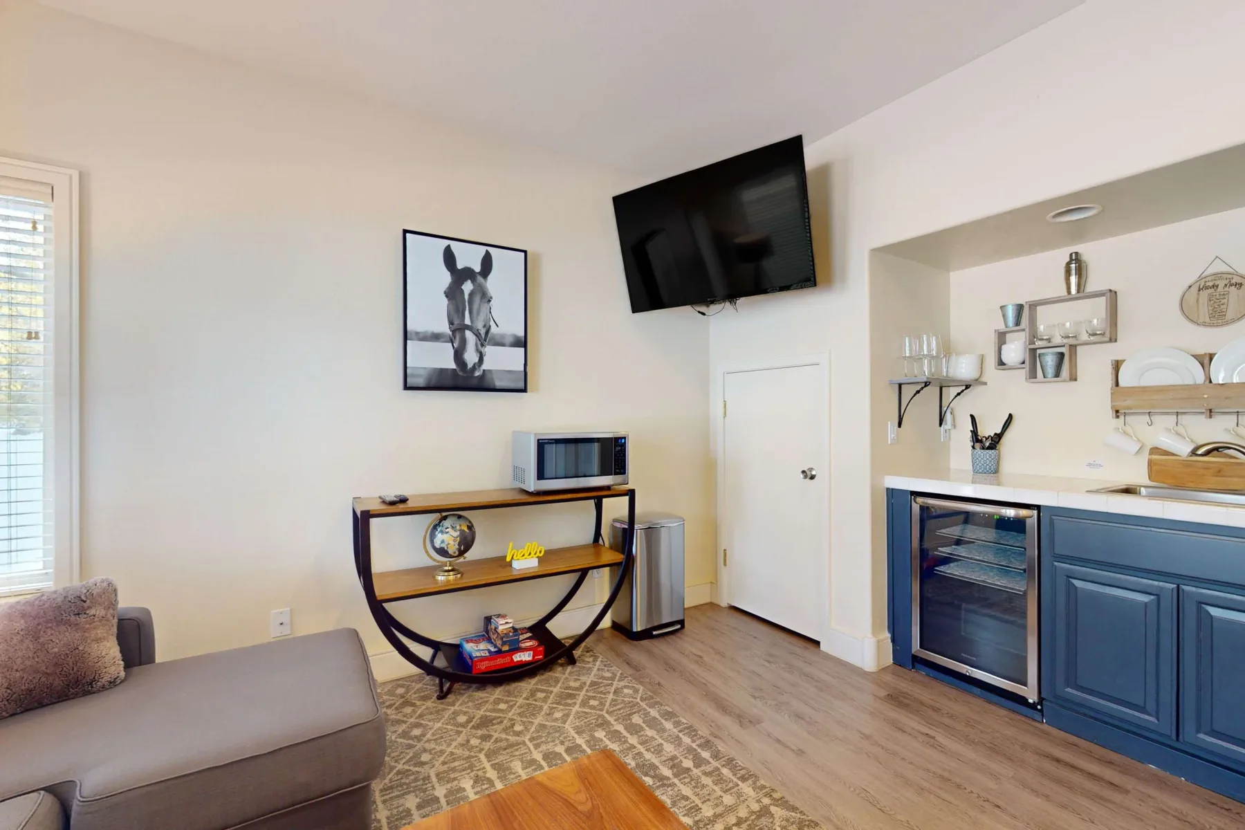 Una sala de estar con un televisor montado en la pared y una pequeña cocina.