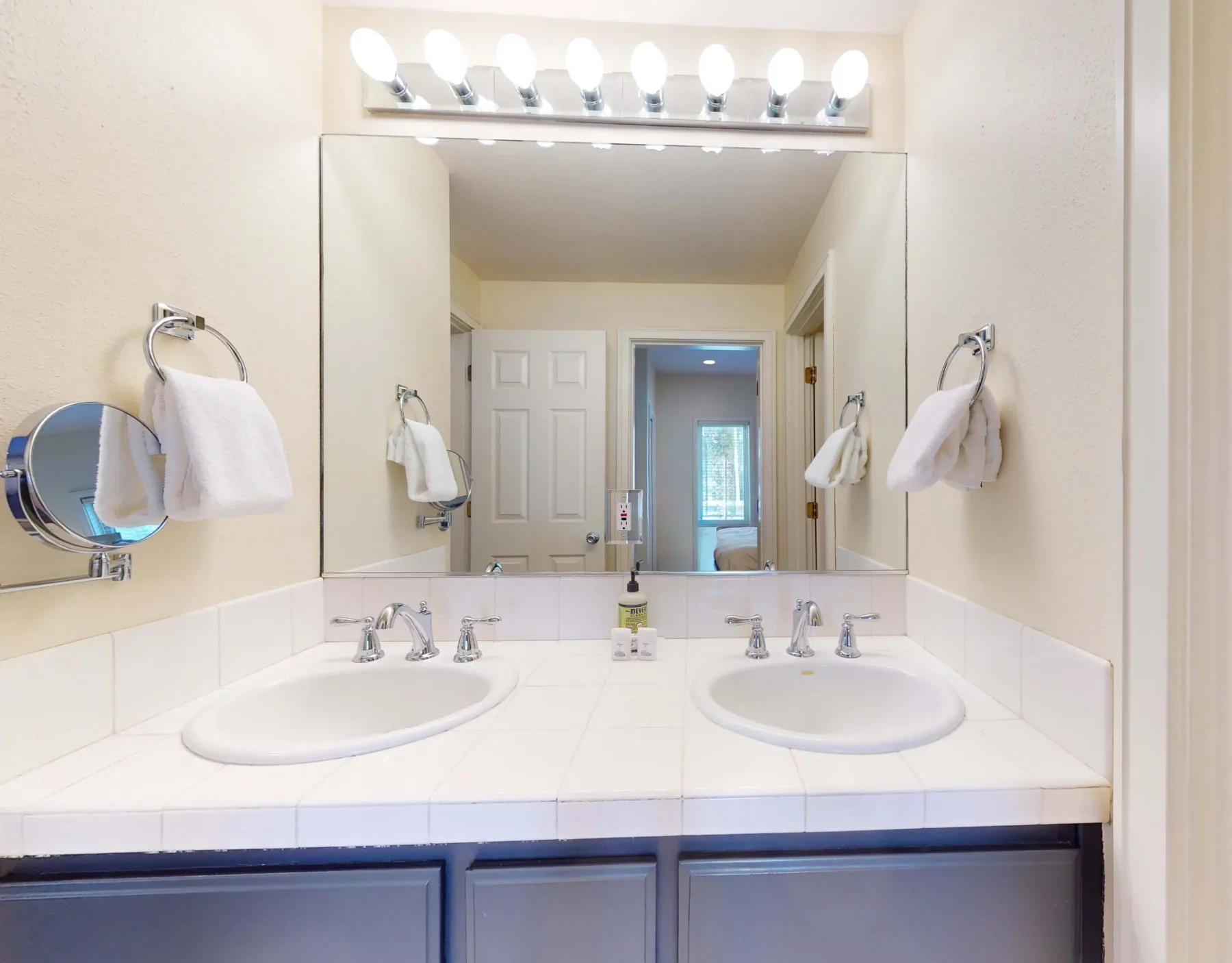 Un tocador de baño con dos lavabos y un espejo grande.