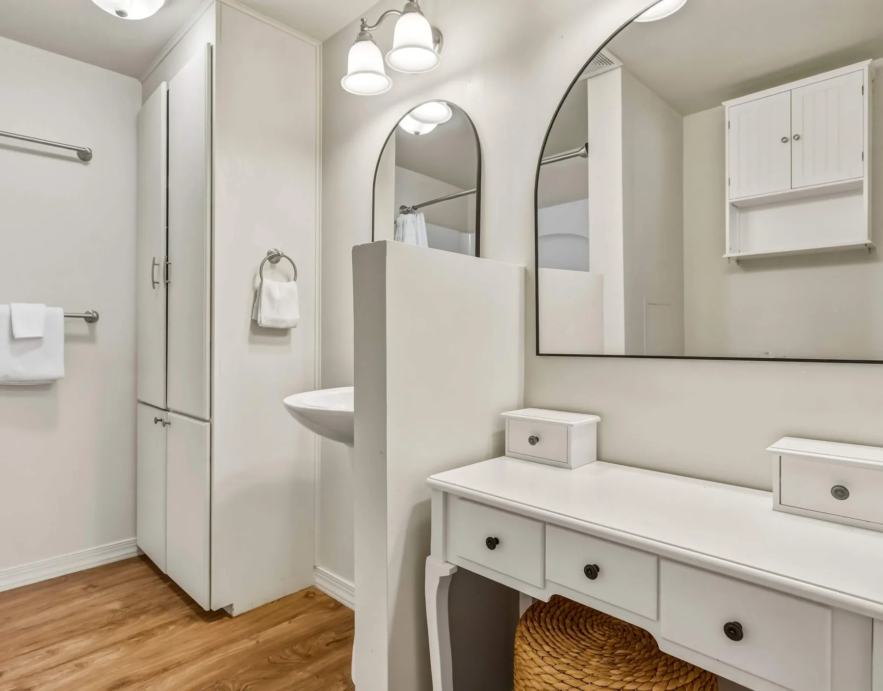 A bright bathroom with a long vanity, mirrors, and a sink.