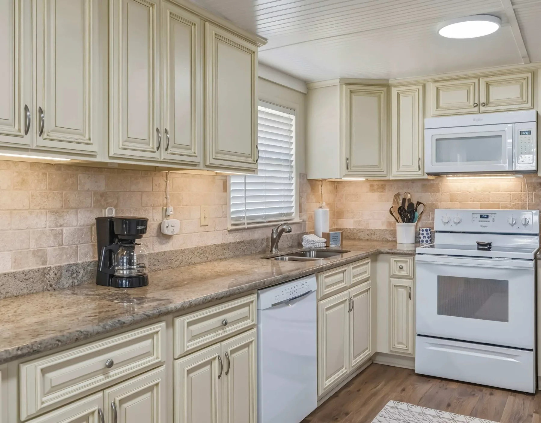 A bright kitchen with pale cabinets, a countertop, and white appliances.