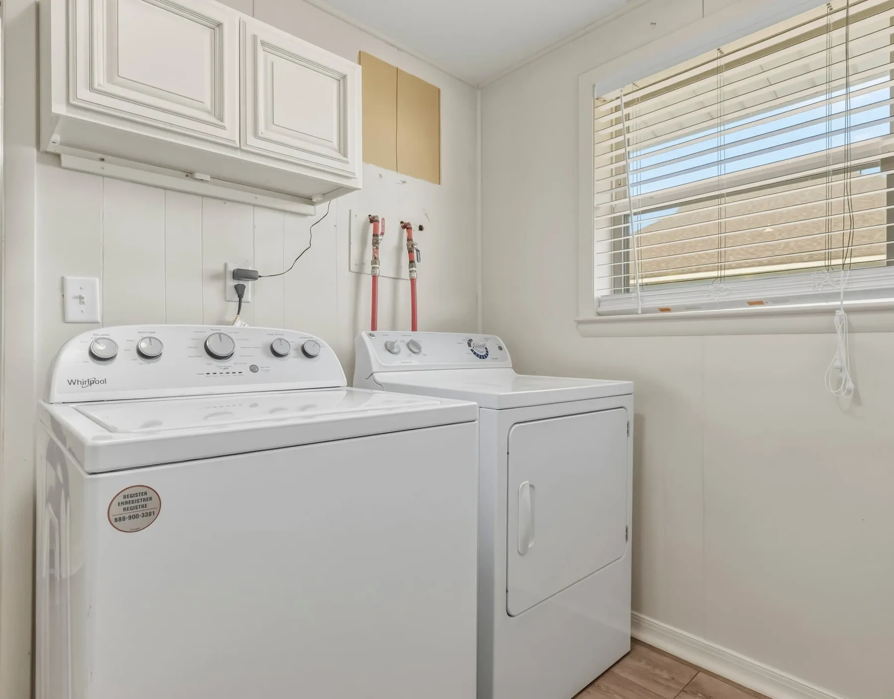 A laundry room with a washer and dryer beneath a window.