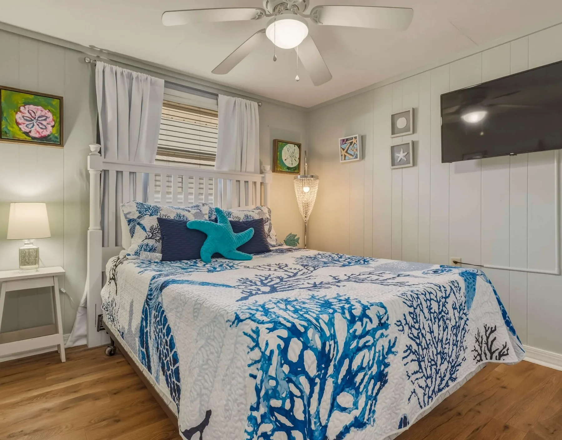 A bedroom with blue-and-white patterned bedding and a wall-mounted television.