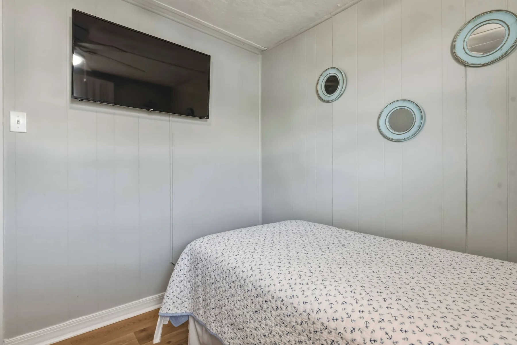 A bedroom with a bed beneath a wall-mounted television and circular wall decorations.