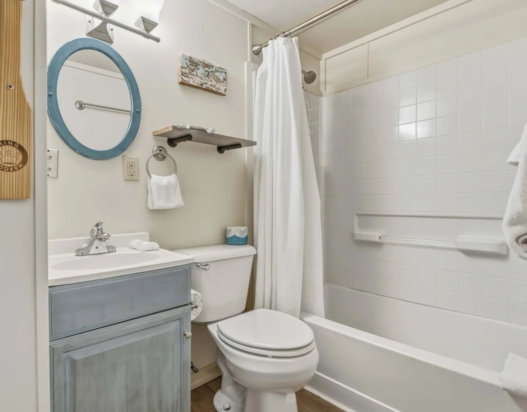 A bathroom with a vanity, toilet, and bathtub behind a shower curtain.