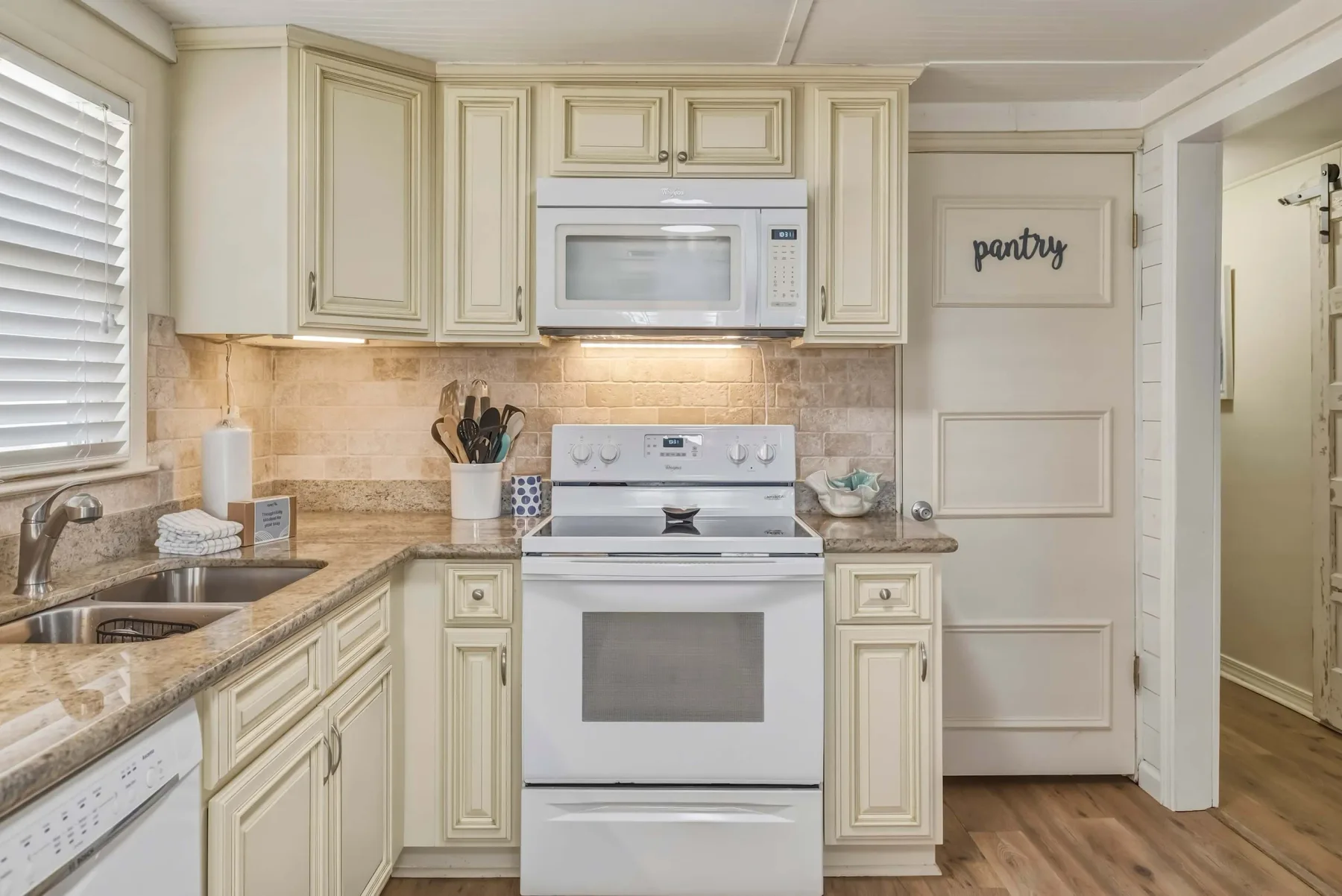 A bright kitchen with cream cabinets, a stove, and a countertop beneath the window.