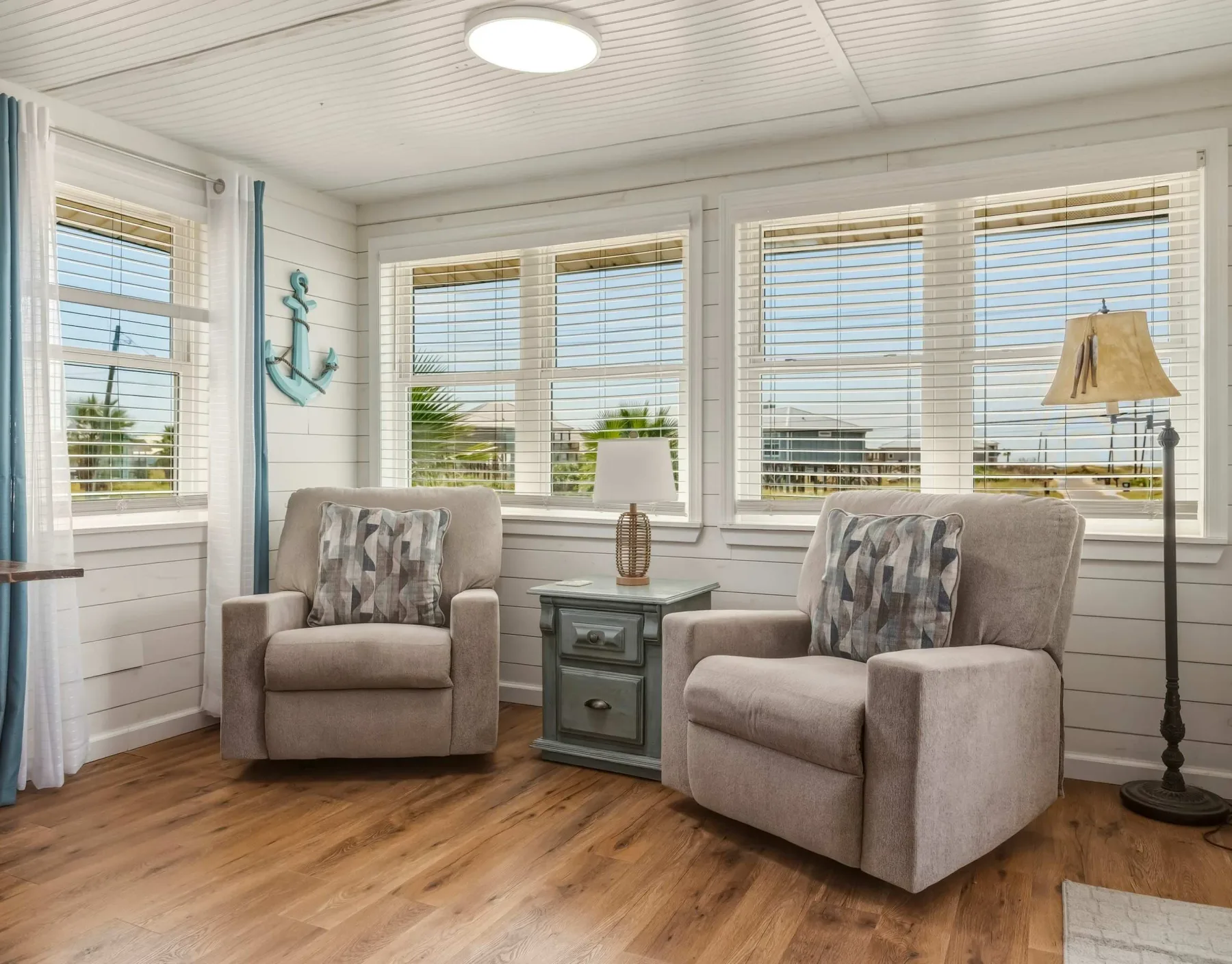 A bright sitting area with two upholstered seats beside wide windows.