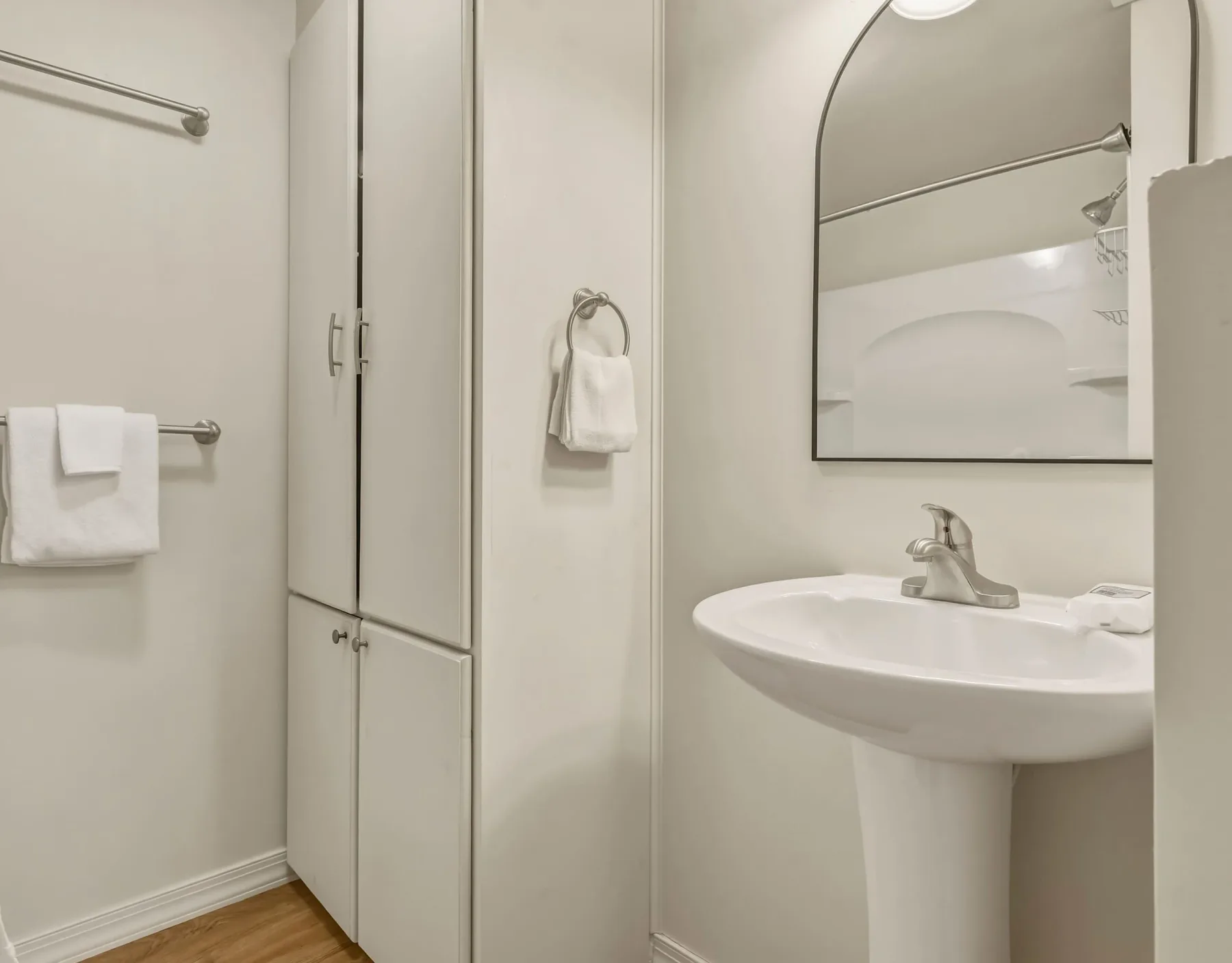 A bathroom with a sink, mirror, and towels on wall rails.