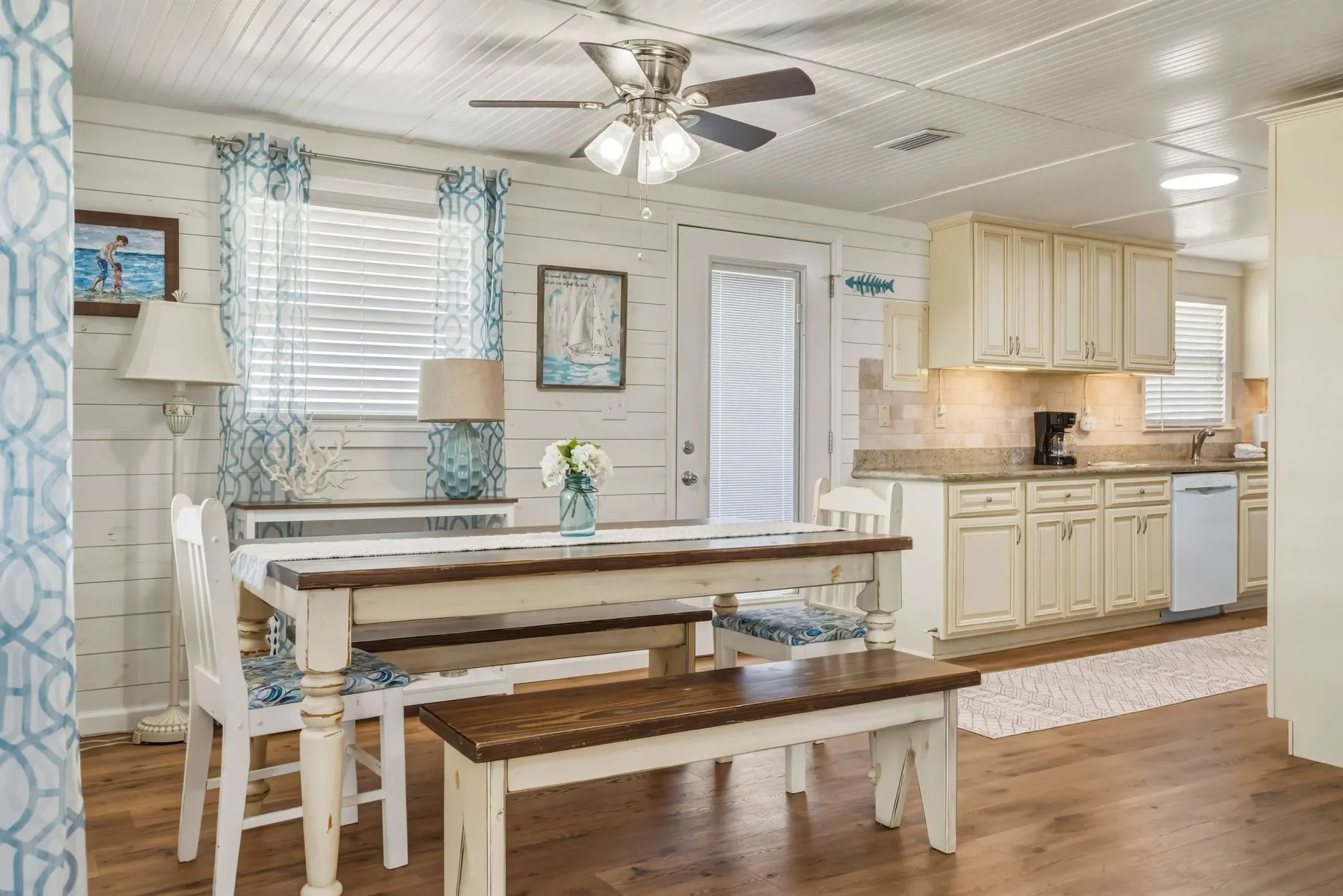 A bright dining area opens onto a kitchen with pale cabinetry.