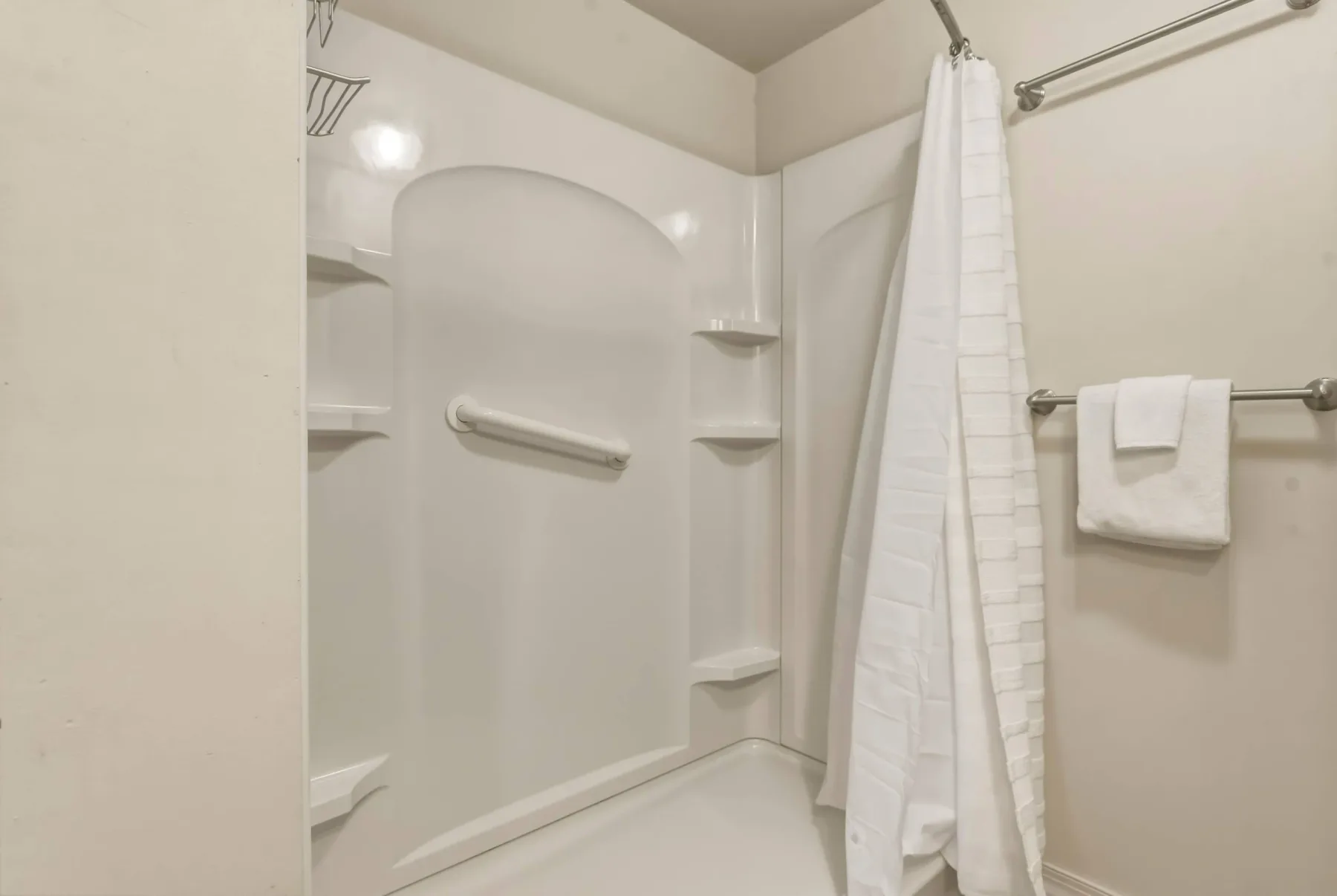 A bathroom shower area with a curtain and built-in shelves.