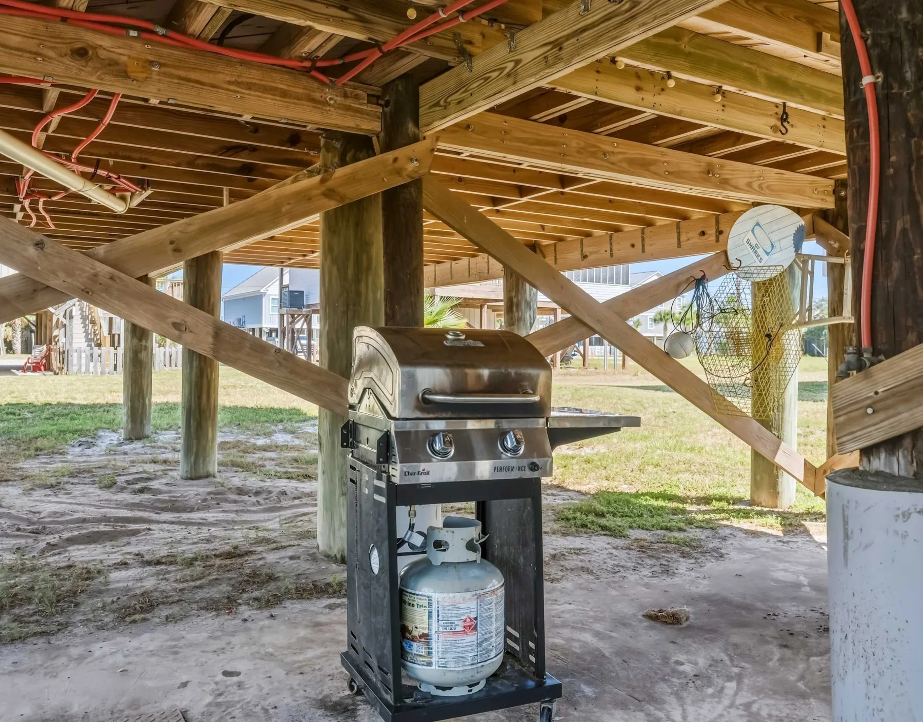 A grill sits beneath a raised wooden deck, with open space around it.