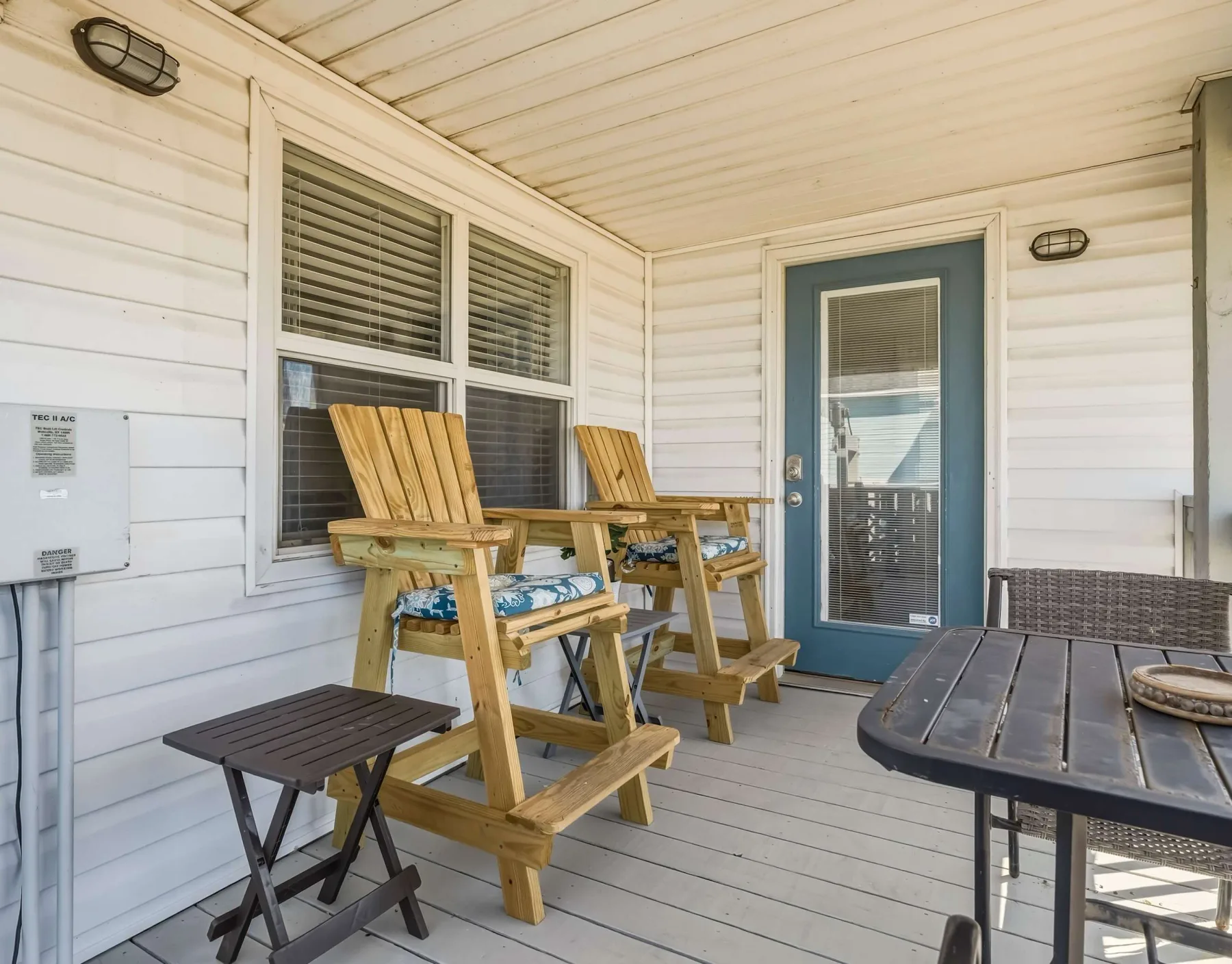 A covered porch with wooden seating, a small table, and a glass-paneled door.