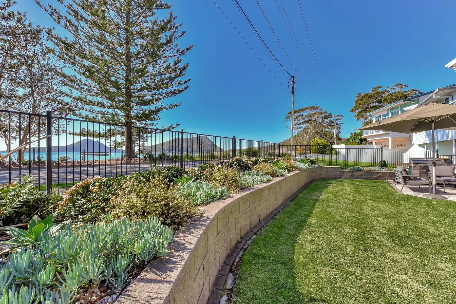 A landscaped garden with a lawn, planted beds, and a view toward the water.