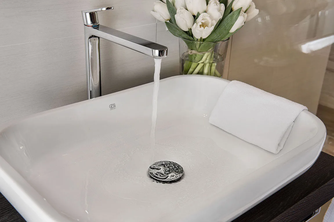 Espacio representativo del hotel: Lavabo de baño con agua corriendo y una toalla doblada.