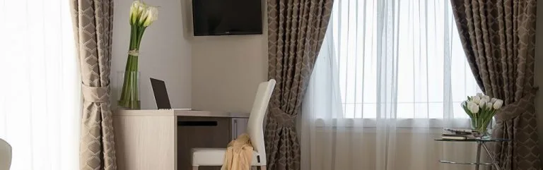 Espacio representativo del hotel: Una zona de escritorio y asientos está junto a una ventana luminosa con cortinas.