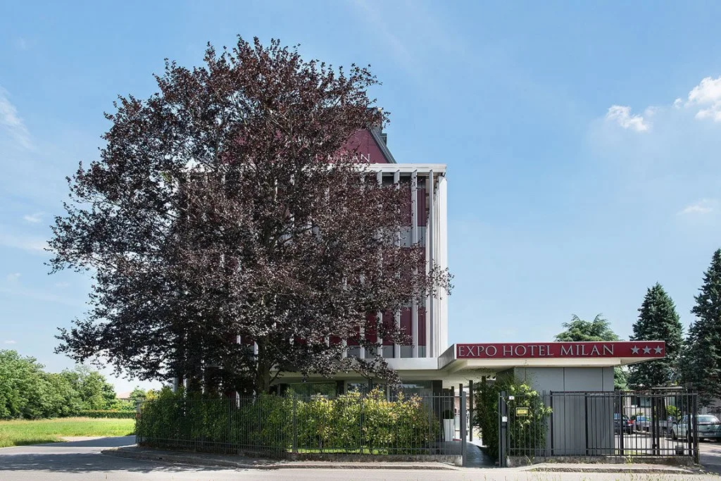 Espacio representativo del hotel: Exterior de un hotel con un árbol frondoso junto a la entrada.