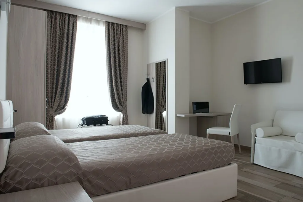 Espacio representativo del hotel: Un dormitorio de hotel con una cama, un escritorio y un televisor en la pared.
