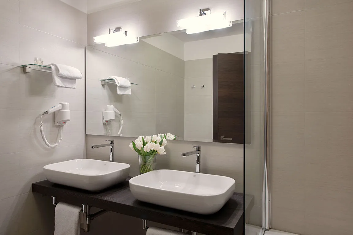 Espacio representativo del hotel: Un tocador de baño con dos lavabos, espejos y flores.