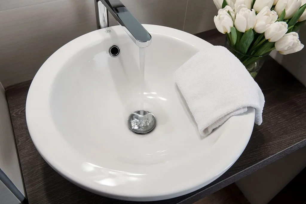 Espacio representativo del hotel: Un lavabo de baño con una toalla doblada y flores blancas al lado.