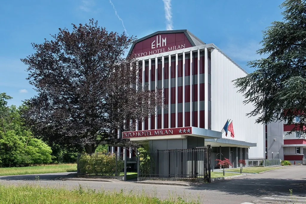 Espacio representativo del hotel: Exterior de un hotel moderno con una fachada alta a rayas y zonas ajardinadas.