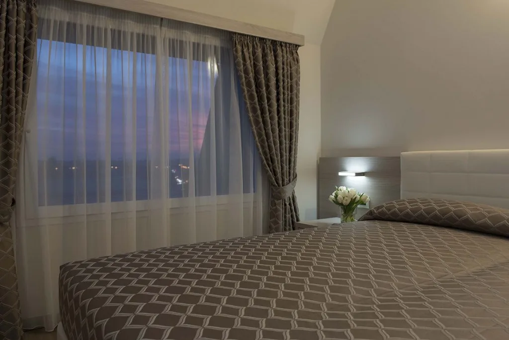 Espacio representativo del hotel: Dormitorio con ropa de cama estampada junto a una ventana con cortinas.