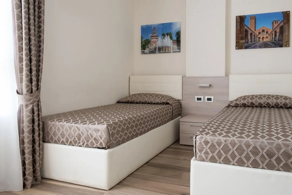 Espacio representativo del hotel: Un dormitorio con dos camas individuales y cuadros enmarcados encima.