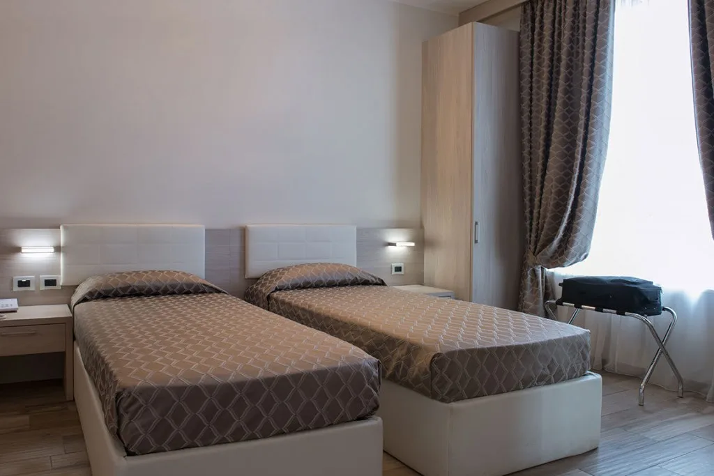 Espacio representativo del hotel: Un dormitorio con dos camas, mesitas de noche y un armario.
