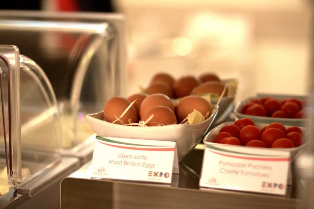 Espacio representativo del hotel: Un bufé de desayuno muestra recipientes con huevos y tomates cherry.