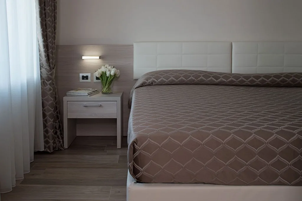 Espacio representativo del hotel: Un dormitorio con una cama tendida y una mesita de noche.