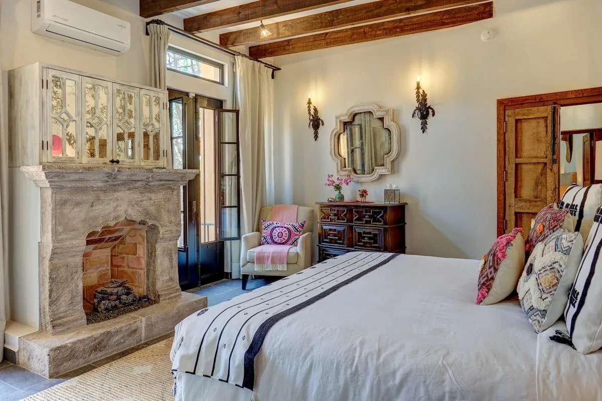 Un dormitorio con una cama grande, una chimenea de piedra y una cómoda pequeña.