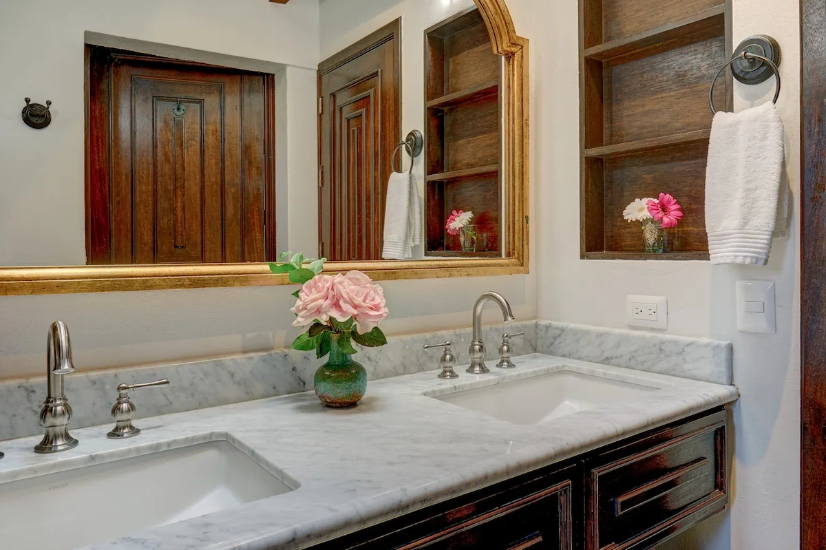 Un tocador de baño con encimera de mármol, lavabo y espejo.