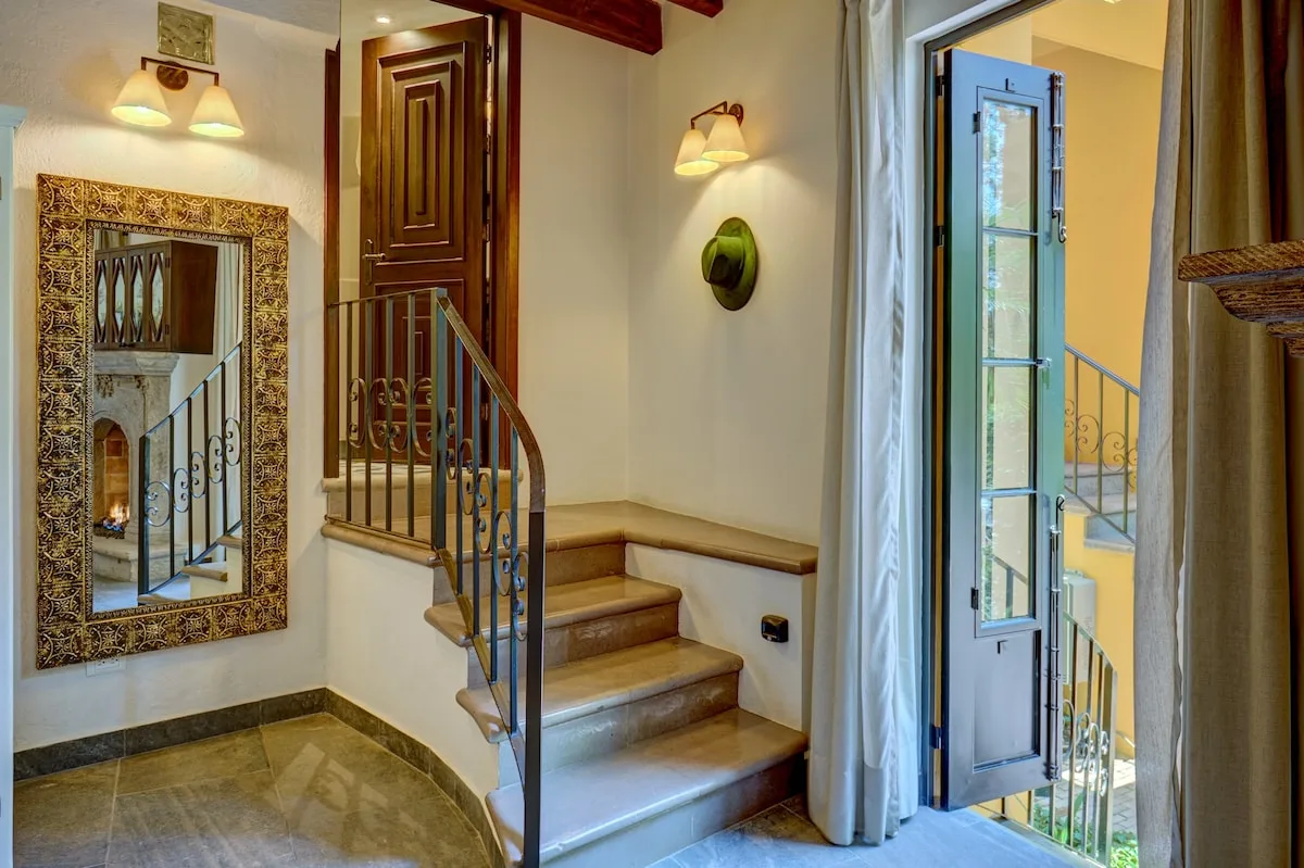 Una entrada interior con una escalera y una puerta acristalada abierta.