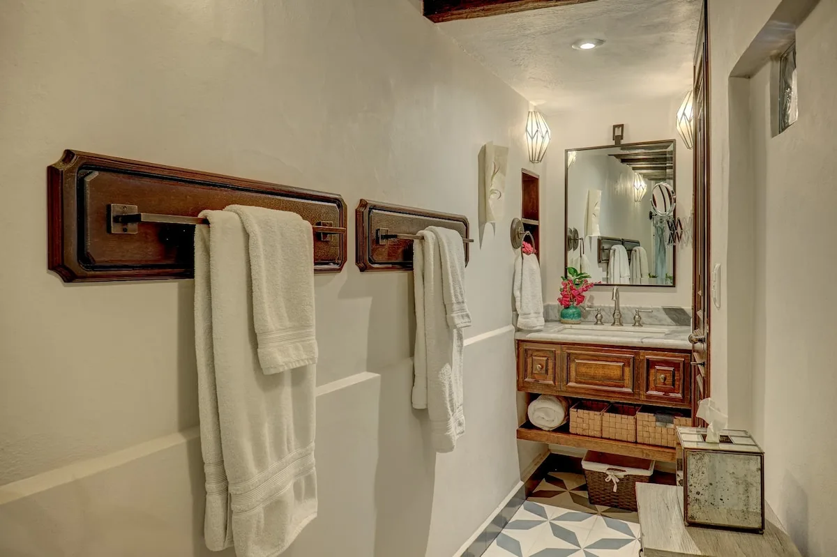 Un baño con lavabo, espejo y toallas colgadas en la pared.