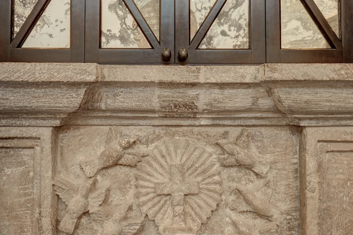 Un panel de piedra tallada está debajo de ventanas de madera oscura.