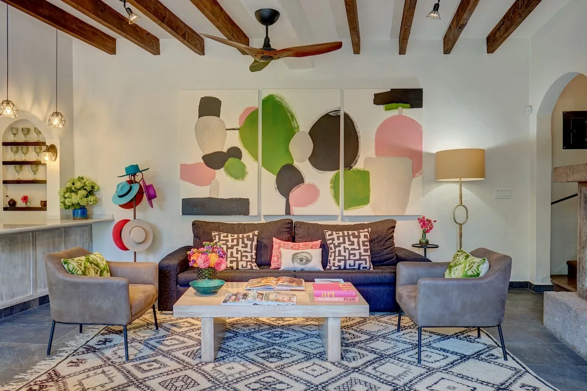 Una sala de estar con un sofá, asientos y una colorida obra abstracta en la pared.