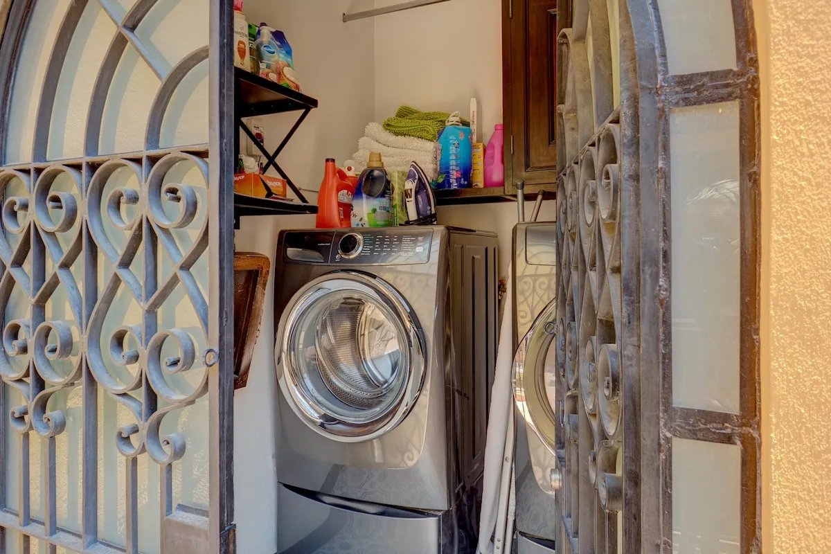 Zona de lavandería con lavadoras y productos de limpieza en un estante.