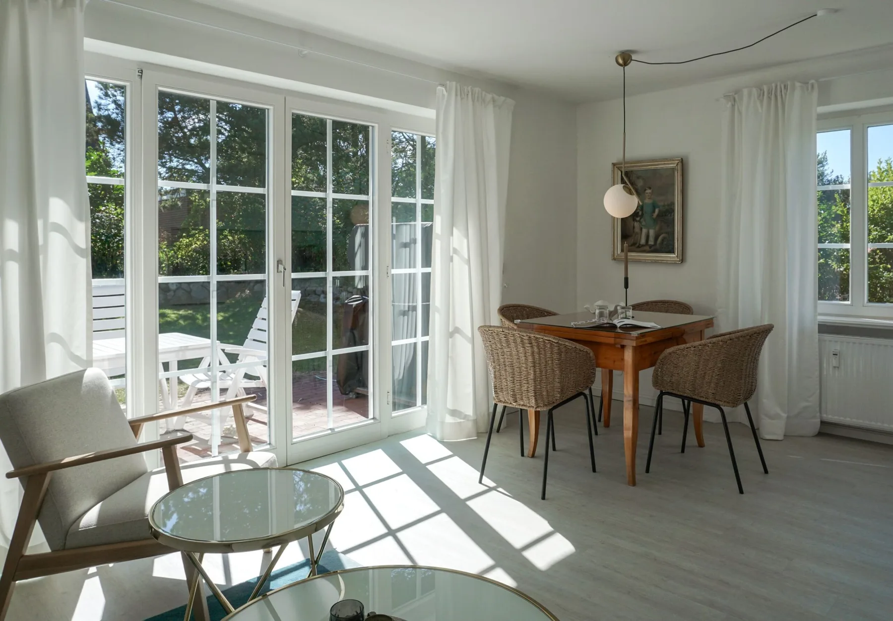Un luminoso comedor y sala de estar con una mesa de madera junto a grandes puertas de vidrio.