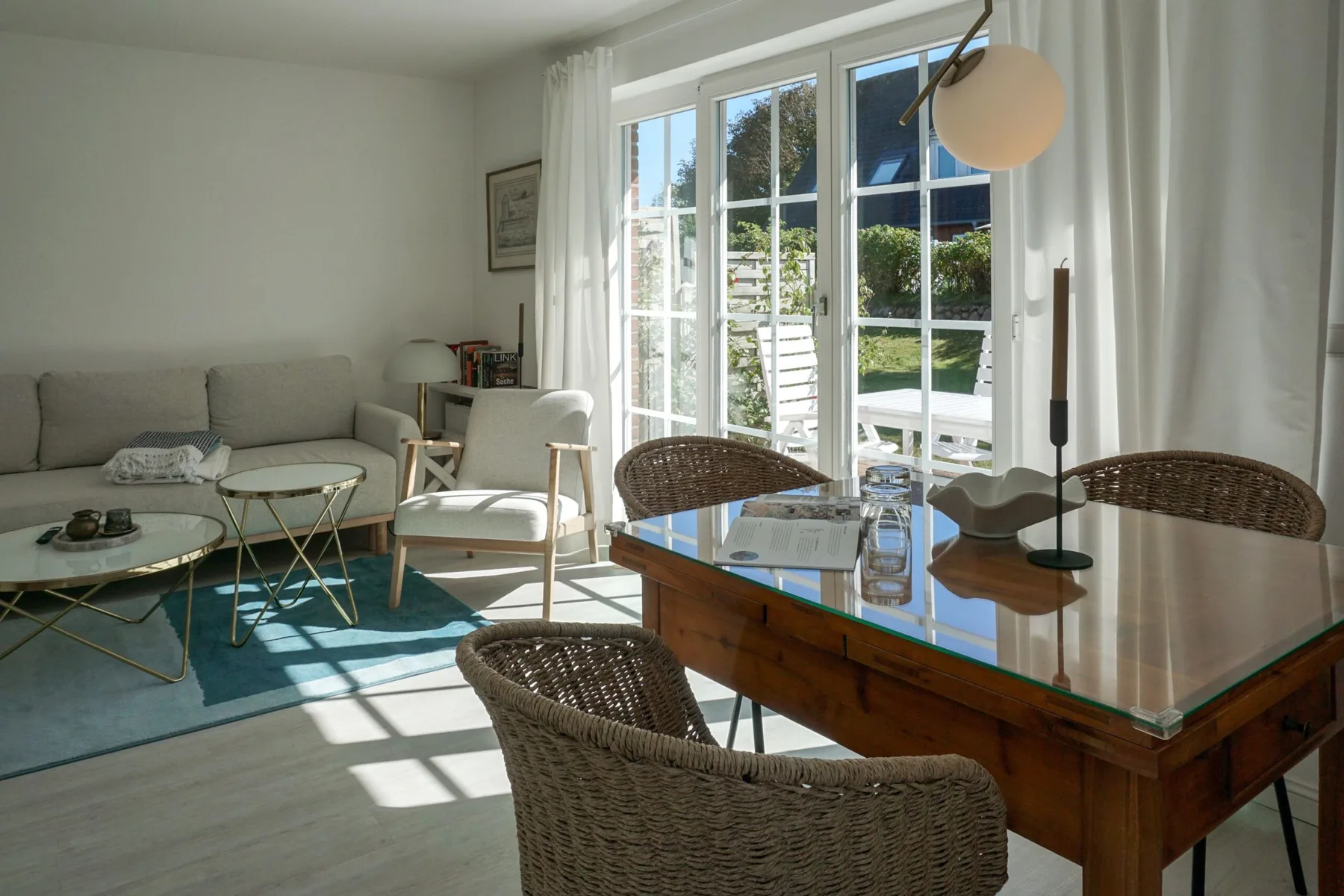 Una luminosa sala de estar y comedor se abre al jardín mediante grandes puertas de vidrio.