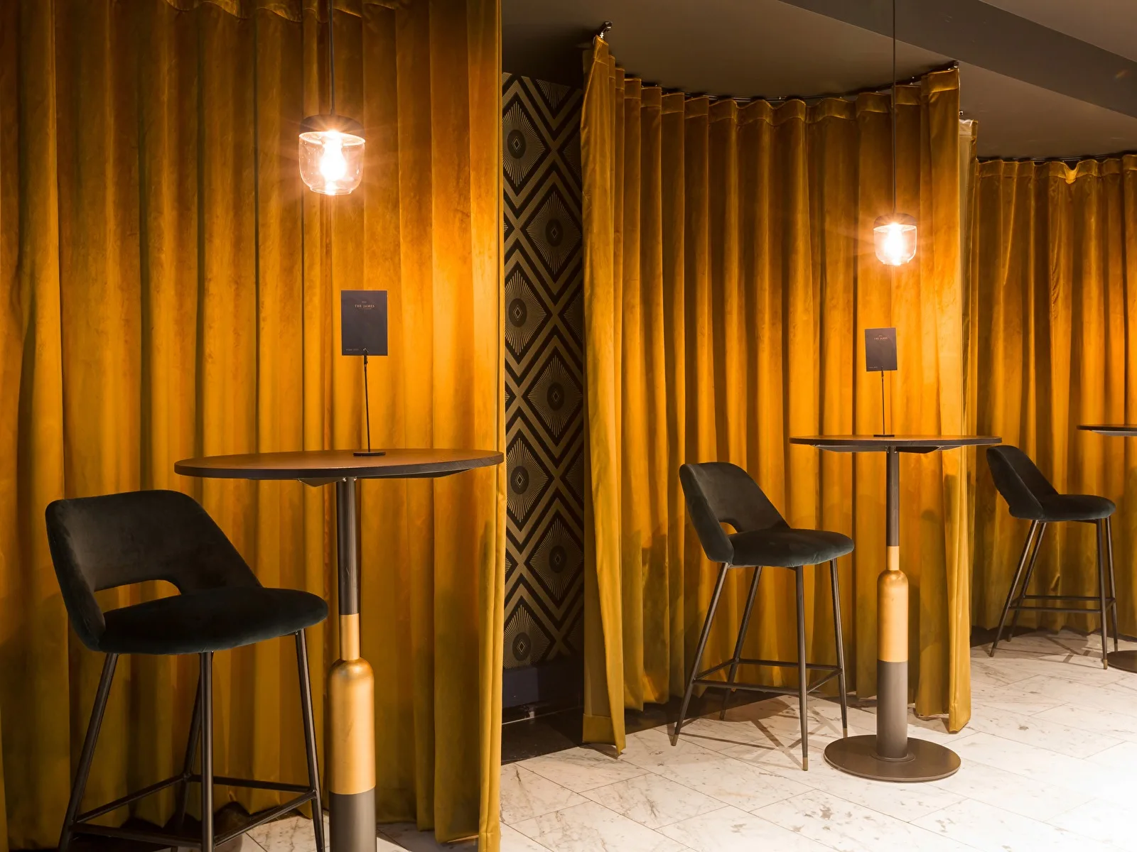 Representative hotel space: A curtained seating area with tall tables and stools.