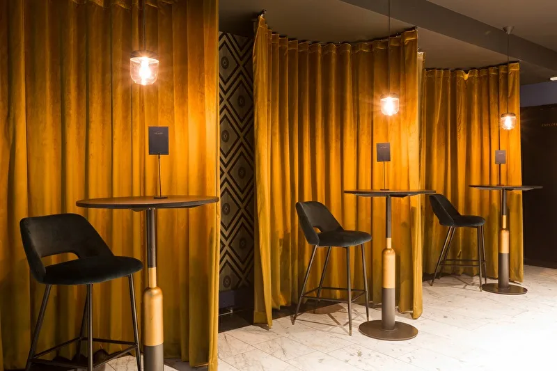 Representative hotel space: A seating area with small tables and golden curtains.