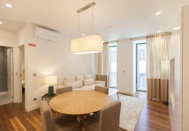 A bright living and dining area with a round table and seating.