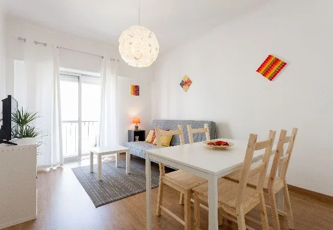 A bright living and dining area with a table, seating, and a balcony door.